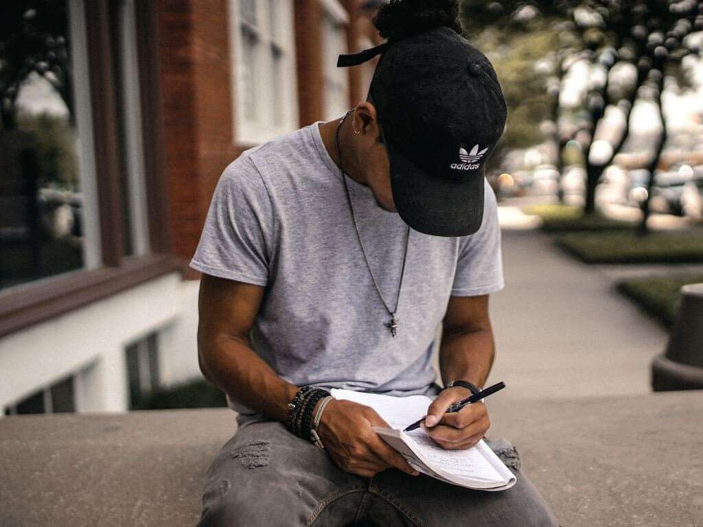 man with black hat writing notes